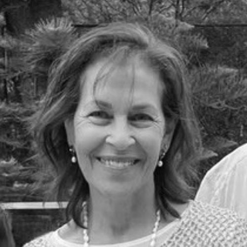 Black and white image of Rolene Fain smiling in front of some trees.