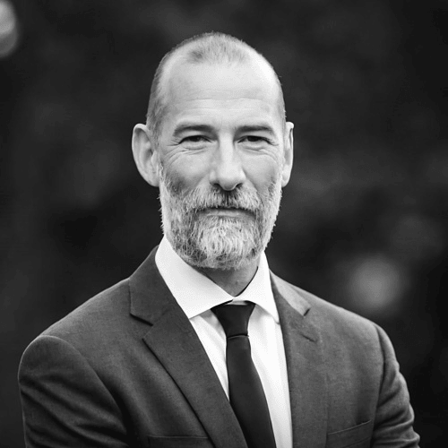 Black and white profile image of Simon Mariner in a suit and tie.