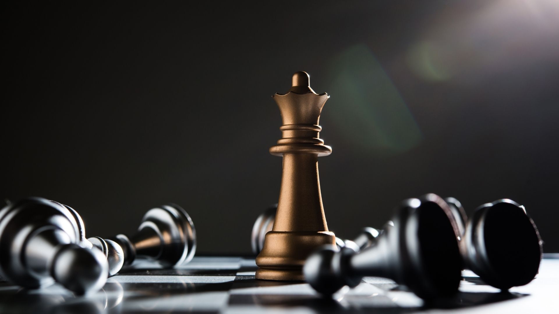 A chess board with a gold king piece surrounded by toppled black pawns.