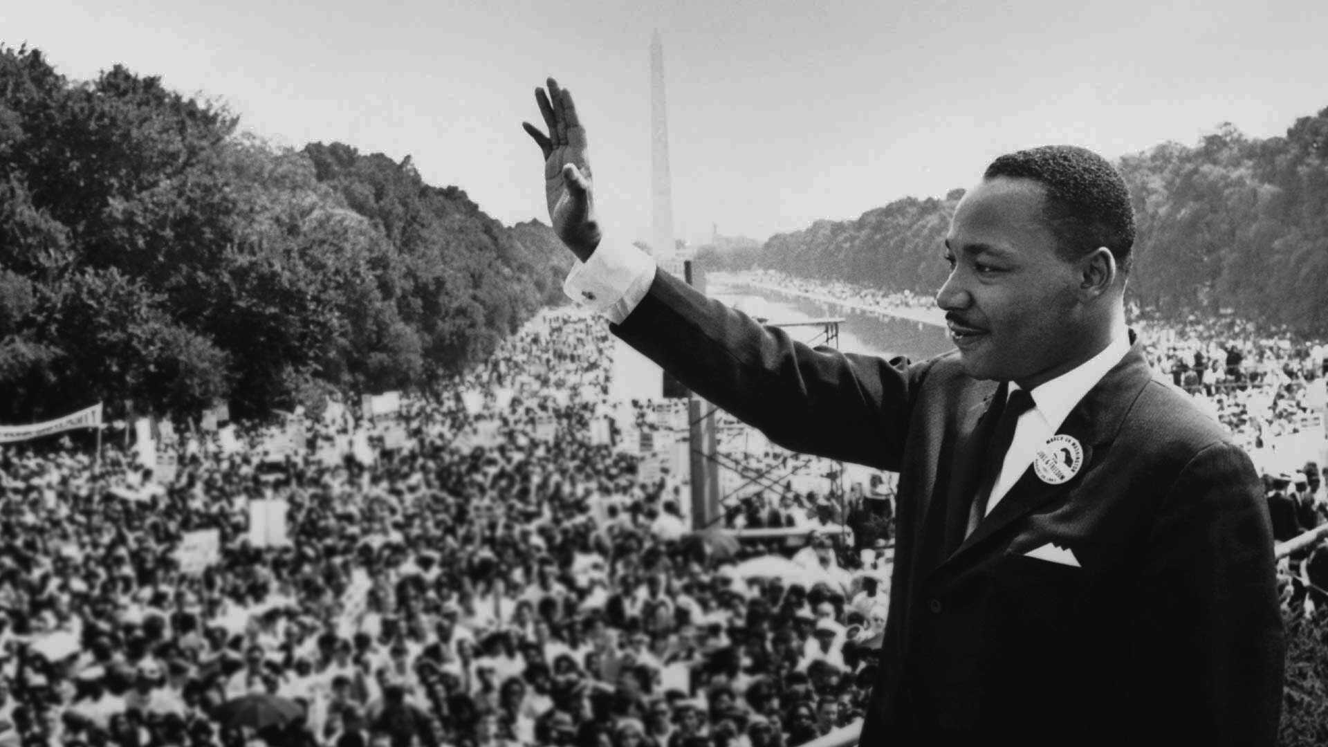 Black and white image of Martin Luther King Jr, delivering his 'I Have a Dream' speech to a huge crowd.